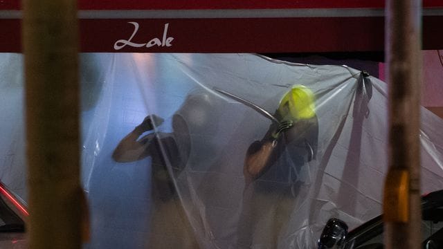 Feuerwehrleute hängen Planen auf.