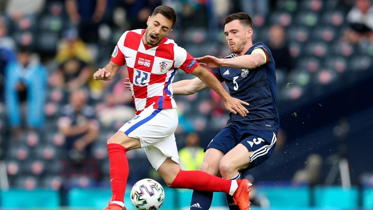 Kroatiens Josip Juranovic (l) und Schottlands Andrew Robertson kämpfen um den Ball.