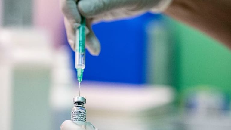 Ein Arzt zieht den Corona-Impfstoff Comirnaty von Biontech/Pfizer in eine Spritze.