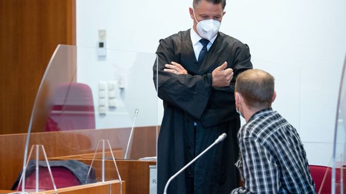 Einer der Angeklagten (r) unterhält sich vor Prozessbeginn mit seinem Verteidiger Dietmar Bonn.