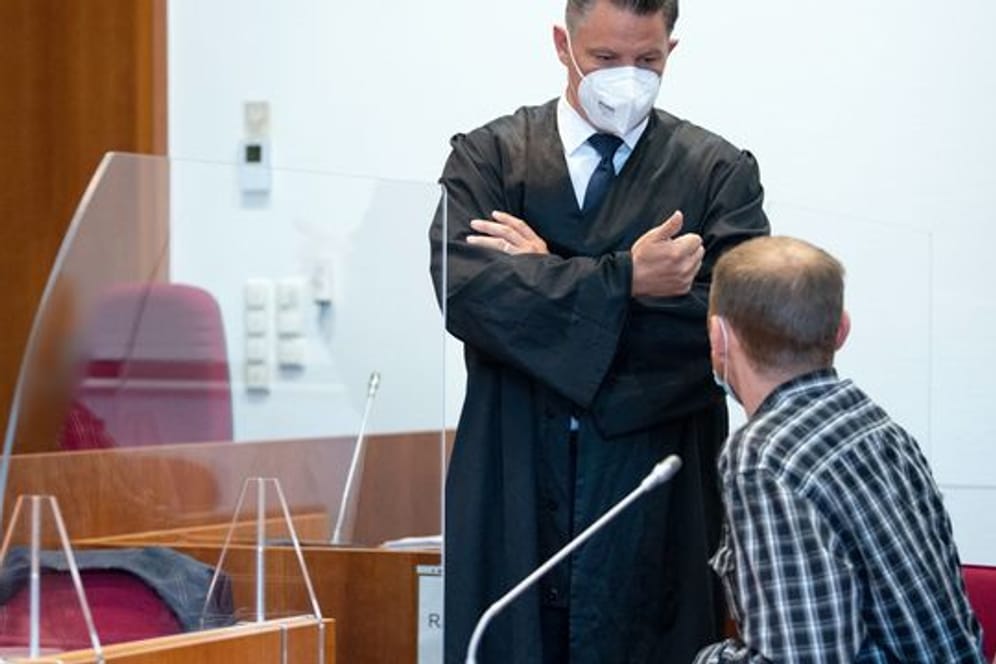 Einer der Angeklagten (r) unterhält sich vor Prozessbeginn mit seinem Verteidiger Dietmar Bonn.
