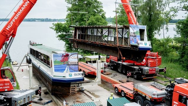 Zwei Mobilkrane heben ein Teilstück des längsseitig zersägten Fahrgastschiffes "MS Oldenburg" am Zwischenahner Meer auf einen Tieflader.