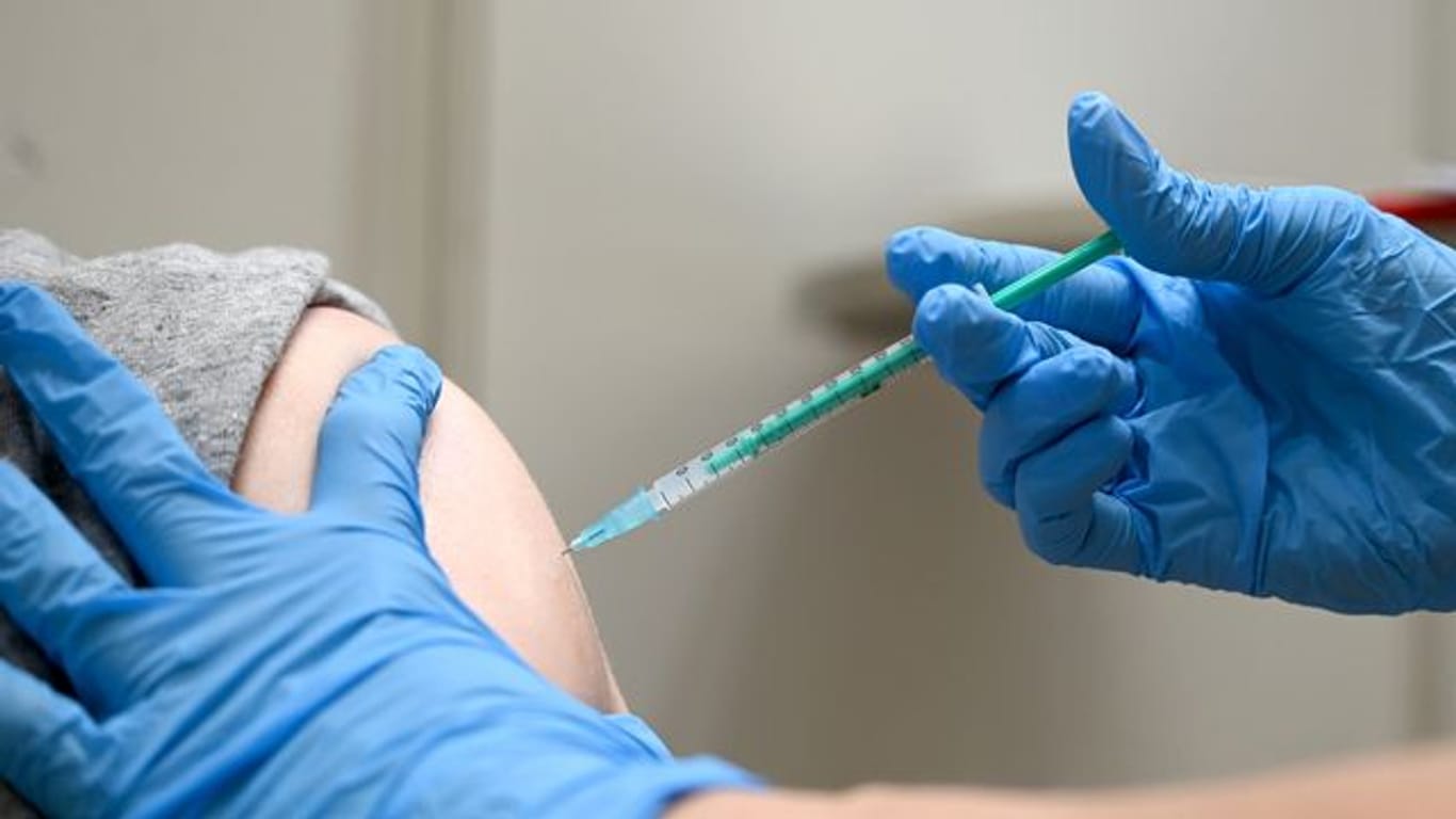 Eine Ärztin impft einen Mann mit einem Corona Impfstoff.