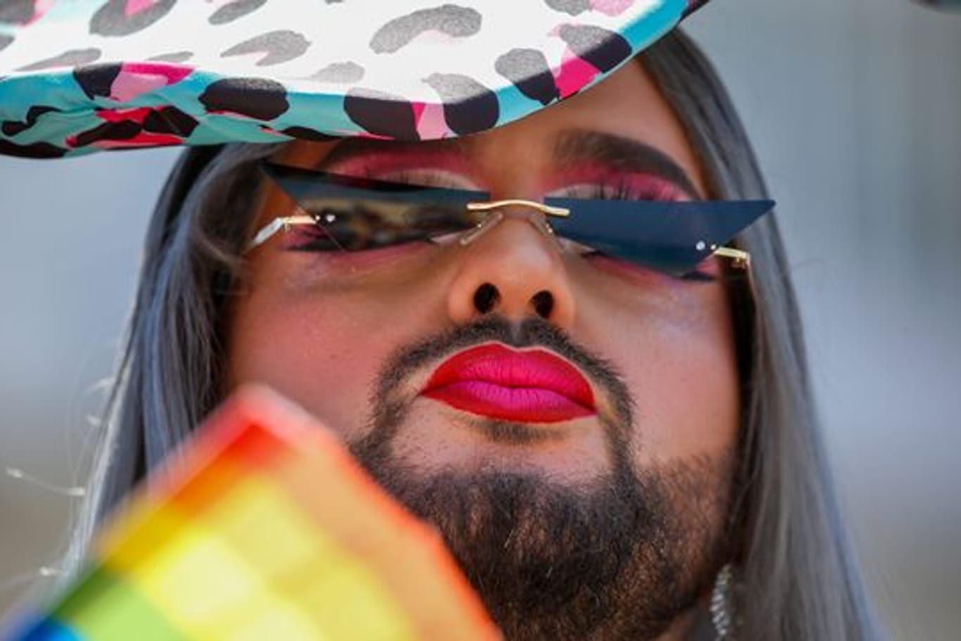 Ein Teilnehmer fächert sich bei der jährlichen Pride Parade Luft mit einem regenbogenfarbenen Fächer zu.