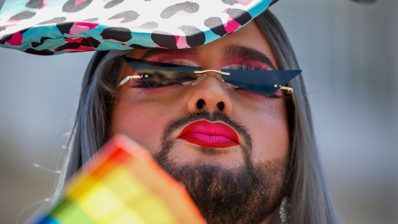 Ein Teilnehmer fächert sich bei der jährlichen Pride Parade Luft mit einem regenbogenfarbenen Fächer zu. Ein Teilnehmer fächert sich bei der jährlichen Pride Parade Luft mit einem regenbogenfarbenen Fächer zu.