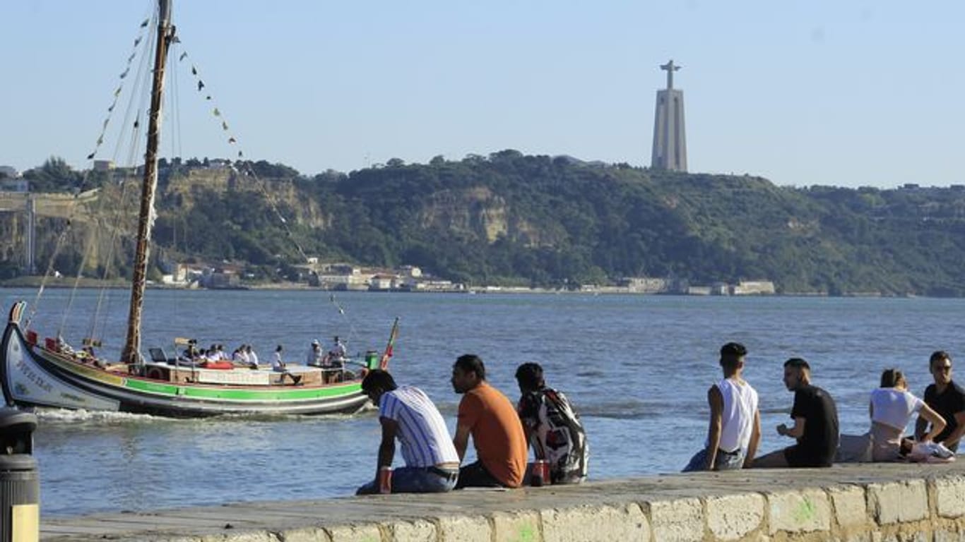 Menschen sitzen an der Küste in Cais do Sodre in Lissabon.