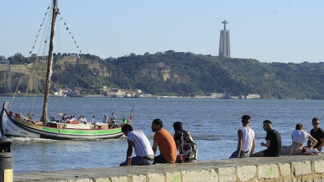 Menschen sitzen an der Küste in Cais do Sodre in Lissabon.