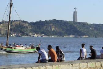 Menschen sitzen an der Küste in Cais do Sodre in Lissabon.