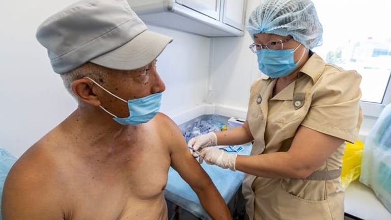 Eine medizinische Mitarbeiterin in Schutzkleidung injiziert einem Mann eine Dosis des Corona-Imfpstoffs Sputnik V in einem mobilen Impfzentrum auf der russischen Insel Sachalin.