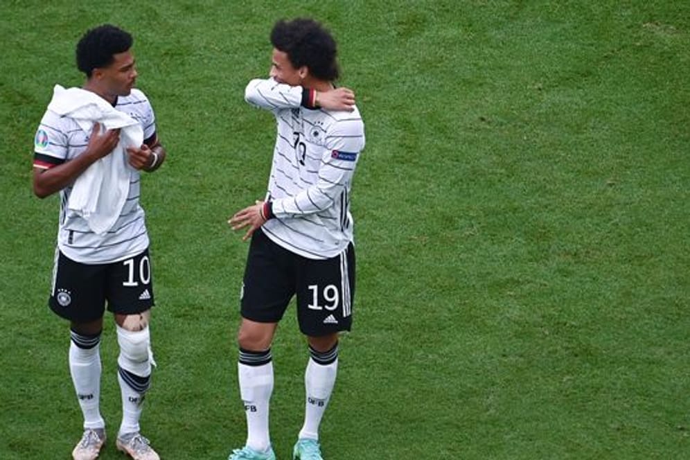 Deutschlands Serge Gnabry und Leroy Sané (r) unterhalten sich nach einer Partie auf dem Platz.