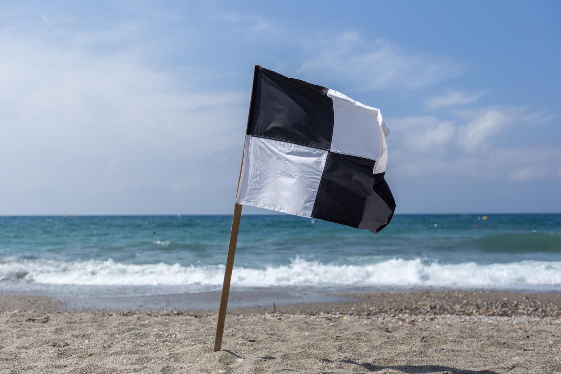 Schwarz-weiße Flagge: Hier ist Schwimmen verboten, denn es handelt sich um eine ausgewiesene Wassersportzone. Der Abschnitt, der von den schwarz-weißen Flaggen eingegrenzt wird, ist reserviert für Strandbesucher mit Surfboard, Segelboot und Co.