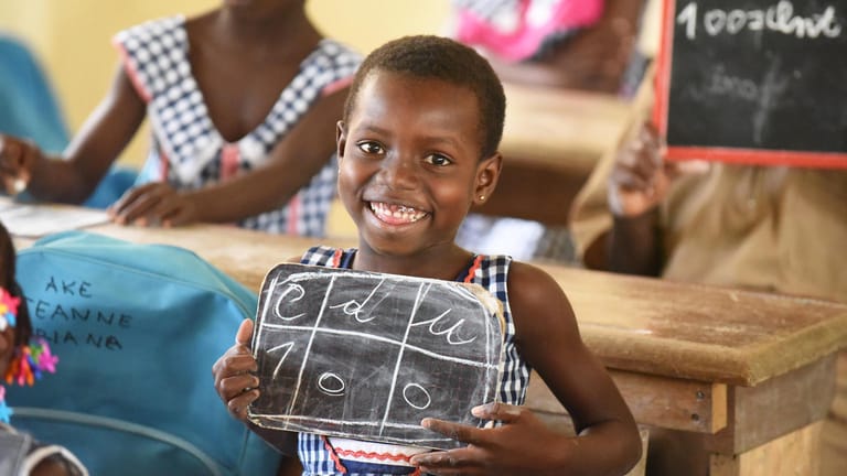 Ein Mädchen in einer Schule in der Elfenbeinküste zeigt, was es auf eine Tafel geschrieben hat.