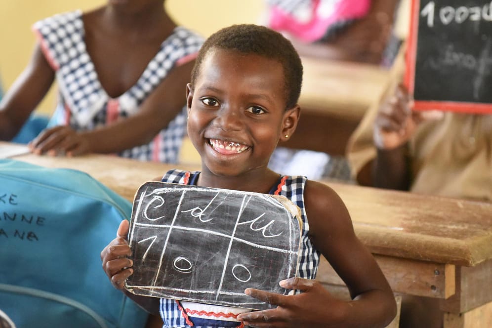 Ein Mädchen in einer Schule in der Elfenbeinküste zeigt, was es auf eine Tafel geschrieben hat.