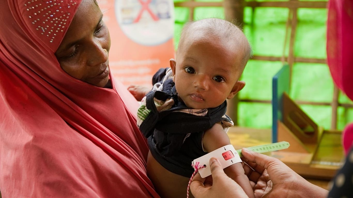 Ein Kleinkind in Bangladesch wird auf Mangelernährung untersucht. Das Maßband zeigt Rot.