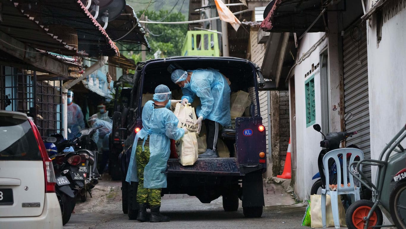 Malaysia: Regierungspersonal verteilt lebenswichtige Vorräte an die Bewohner des Stadtteils Segambut Dalam, der aufgrund des drastischen Anstiegs von Corona-Infektionen abgeriegelt wurde.