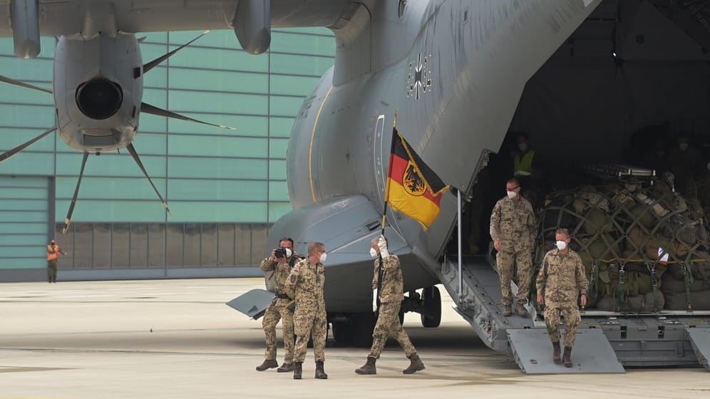 Soldaten der Bundeswehr betreten mit ihrer Truppenfahne deutschen Boden.