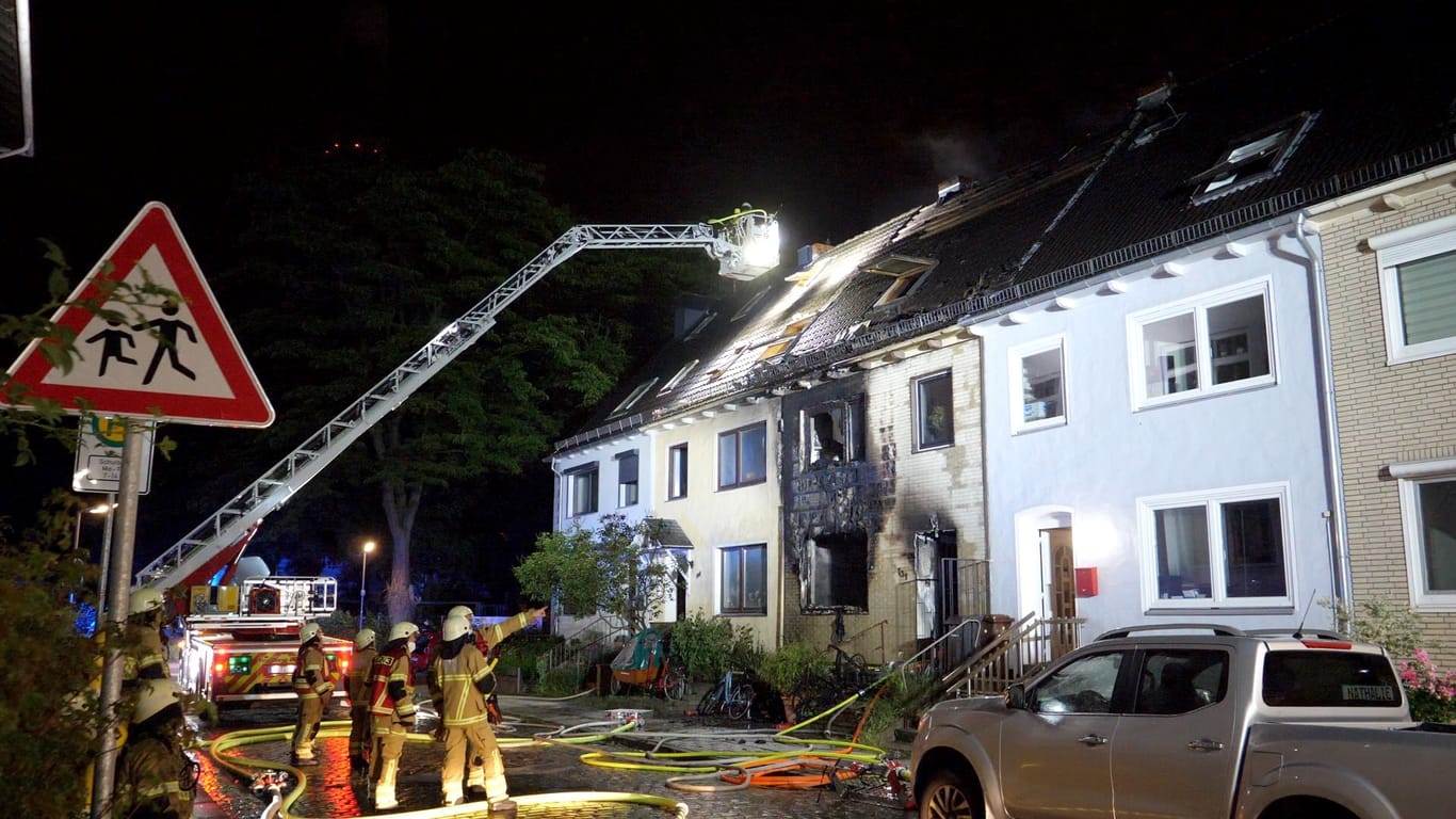 Einsatzkräfte der Feuerwehr stehen vor dem Haus: Von zwei Drehleitern aus haben Helfer die Ausbreitung der Flammen verhindert.