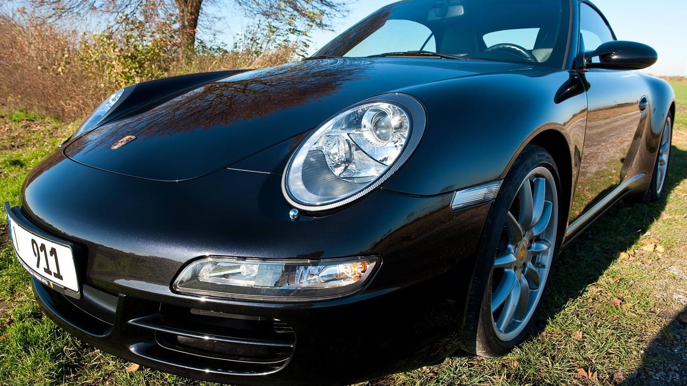 Ein Porsche steht auf einer Wiese (Symbolbild): Die beiden mutmaßlichen Täter hatten es auf die Anzahlungen abgesehen.