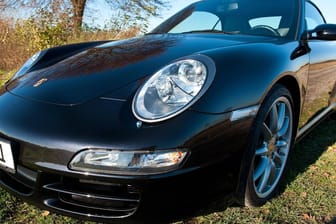 Ein Porsche steht auf einer Wiese (Symbolbild): Die beiden mutmaßlichen Täter hatten es auf die Anzahlungen abgesehen.