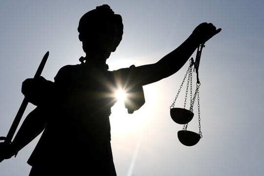 Eine Statue der Justitia hält eine Waage in der Hand