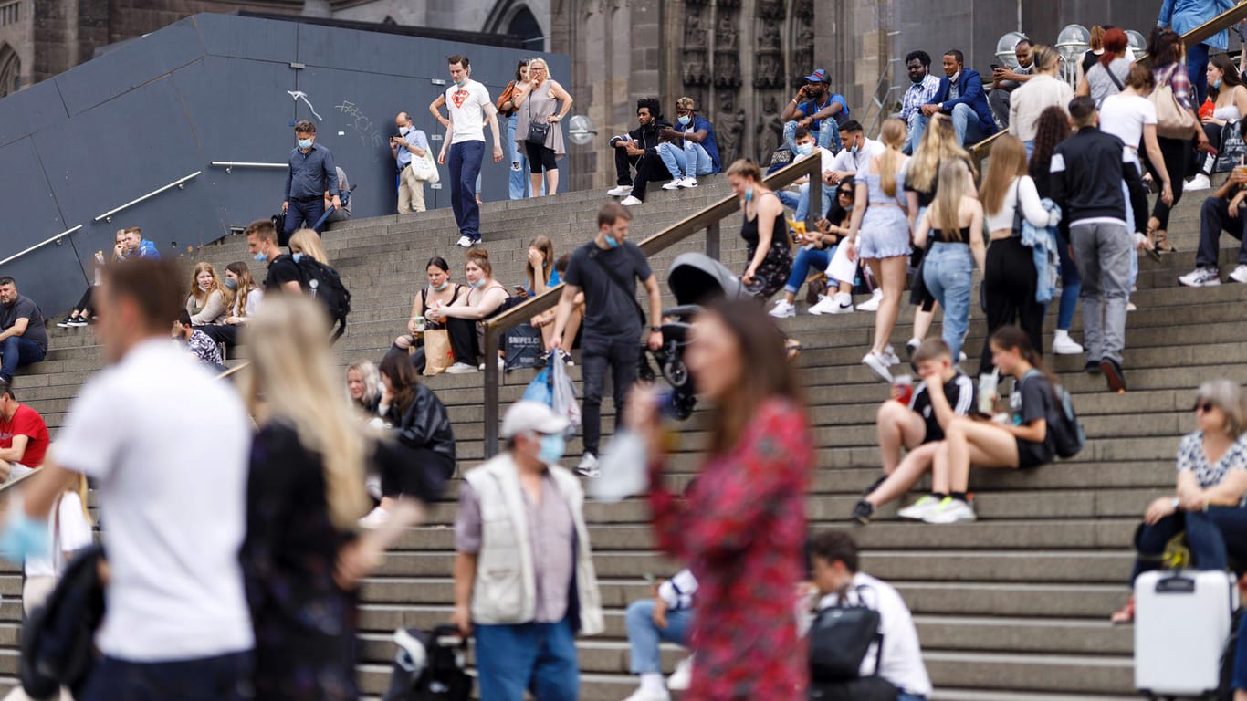 Viele junge Menschen sitzen in der Kölner Innenstadt auf der Domtreppe (Archivbild): Die Kölner Bevölkerung ist im Schnitt mehr als ein Jahr jünger als die der Stadt Düsseldorf.
