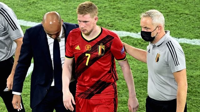 Belgiens Cheftrainer Roberto Martinez (l-r) und Physiotherapeut begleiten Kevin De Bruyne vom Spielfeld.