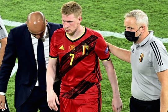 Belgiens Cheftrainer Roberto Martinez (l-r) und Physiotherapeut begleiten Kevin De Bruyne vom Spielfeld.