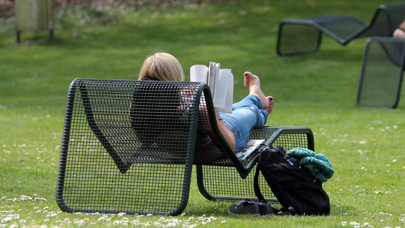 Eine Frau liest ein Buch auf einem Liegestuhl (Symbolbild): In München sollen Stadtterrassen auf öffentlichen Plätzen entstehen.