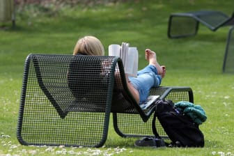 Eine Frau liest ein Buch auf einem Liegestuhl (Symbolbild): In München sollen Stadtterrassen auf öffentlichen Plätzen entstehen.