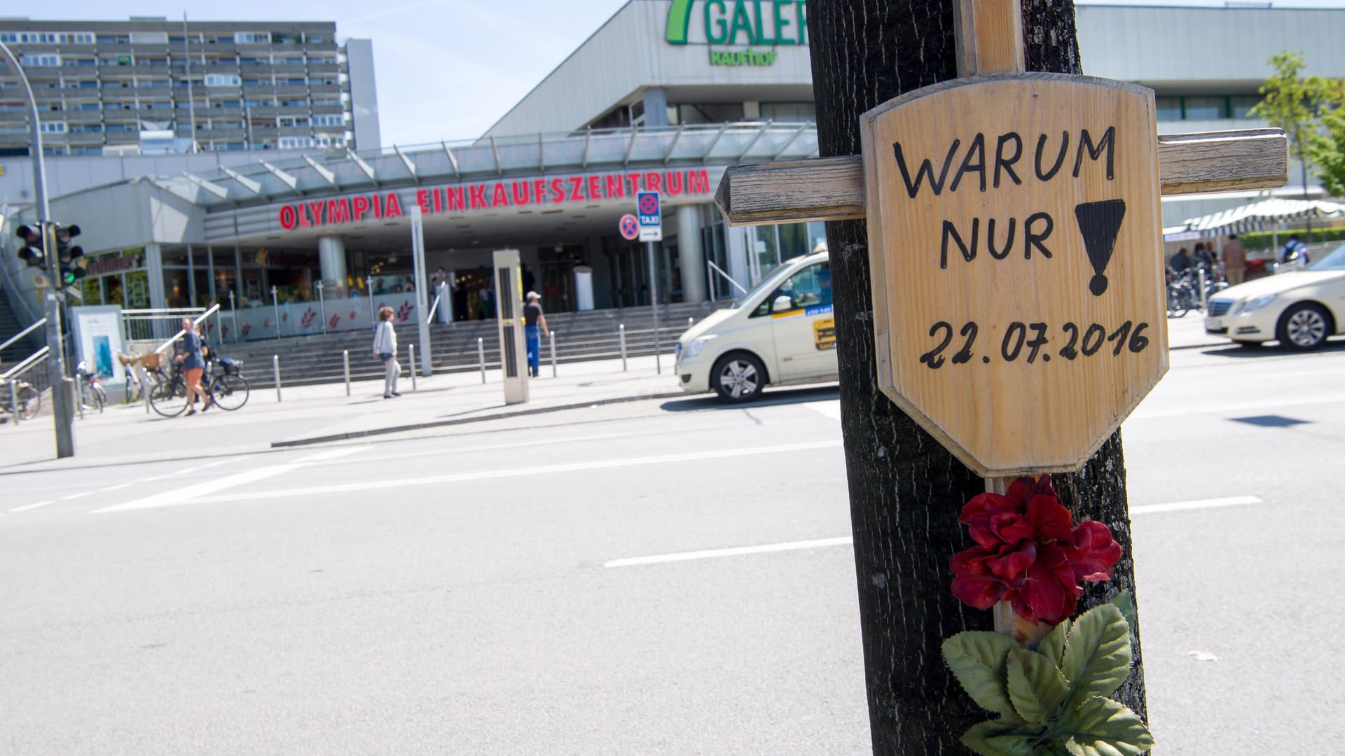 Ein Holzkreuz hängt vor dem Eingang zum Olympia-Einkaufszentrum (Archivbild): Knapp fünf Jahre nach dem rassistischen Anschlag am OEZ in München mit neun Toten und vielen Verletzten sehen Experten immer noch Defizite bei der Aufarbeitung. Ein Holzkreuz hängt vor dem Eingang zum Olympia-Einkaufszentrum (Archivbild): Knapp fünf Jahre nach dem rassistischen Anschlag am OEZ in München mit neun Toten und vielen Verletzten sehen Experten immer noch Defizite bei der Aufarbeitung.
