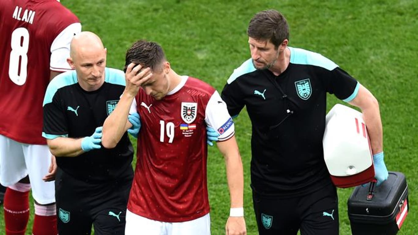 Der am Kopf verletzte Christoph Baumgartner (M) wird nach einer Verletzung von medizinischen Mitarbeitern vom Spielfeld geführt.