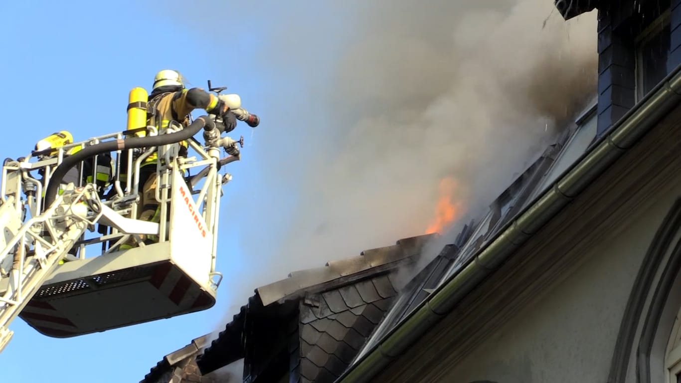 Feuerwehrleute löschen das Feuer im Dachgeschoss von einer Leiter aus. Auch die Bewohner mussten über die Drehleiter aus dem Haus geborgen werden.