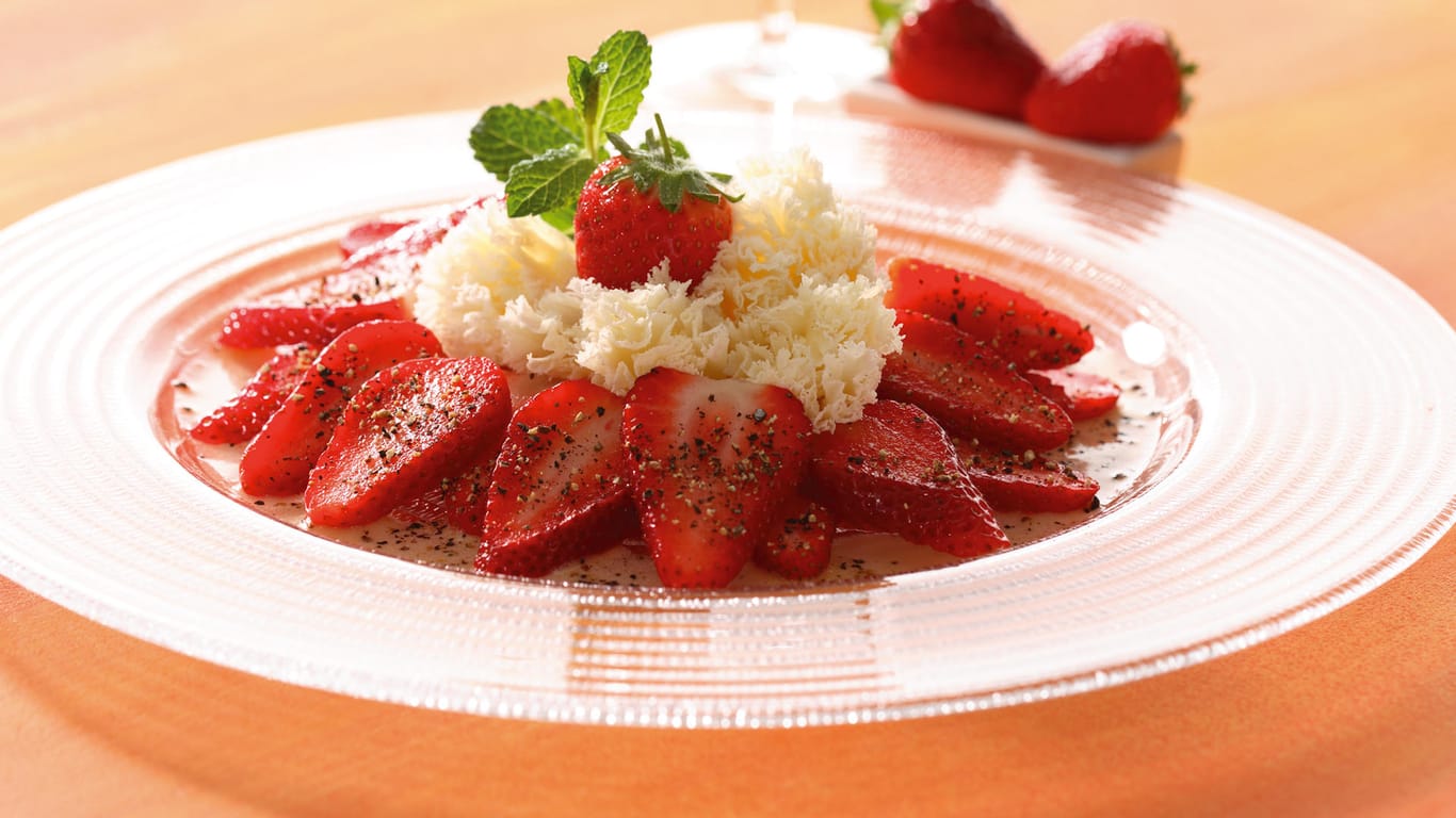Erdbeer-Carpaccio: Die Früchte werden mit einer Himbeerbalsamico-Mischung beträufelt und mit gekräuseltem Tête de Moine-Käse angerichtet.