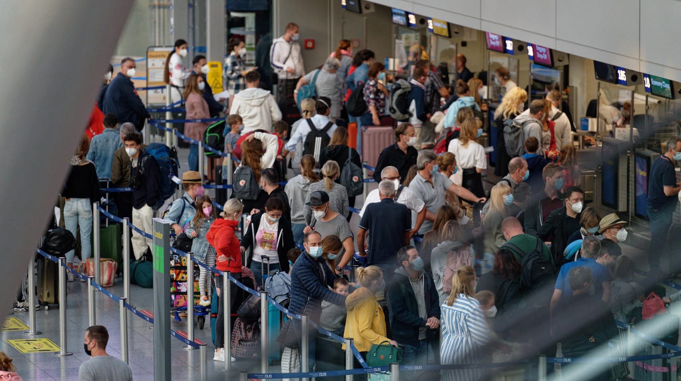 Urlauber stehen mit Koffern in einer Menschenschlange am Check-in Schalter: Am Düsseldorfer Flughafen war es zeitweise so voll, dass die Polizei einschreiten musste.