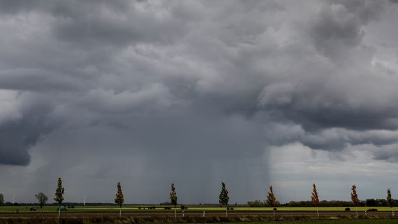 Ein Regenschauer zieht über ein Feld hinweg (Symbolbild): Die Woche startet regnerisch.