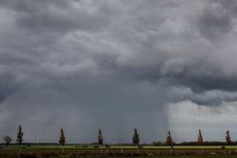 Ein Regenschauer zieht über ein Feld hinweg (Symbolbild): Die Woche startet regnerisch.