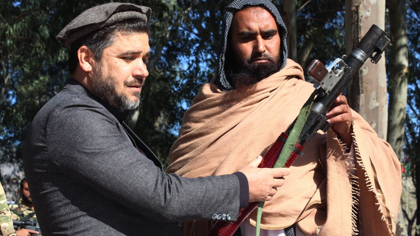 Ein Taliban-Kämpfer (rechts) übergibt ein Gewehr an Regierungsvertreter (Archivbild). Die Rebellen wollen angeblich Friedensgespräche beschleunigen.