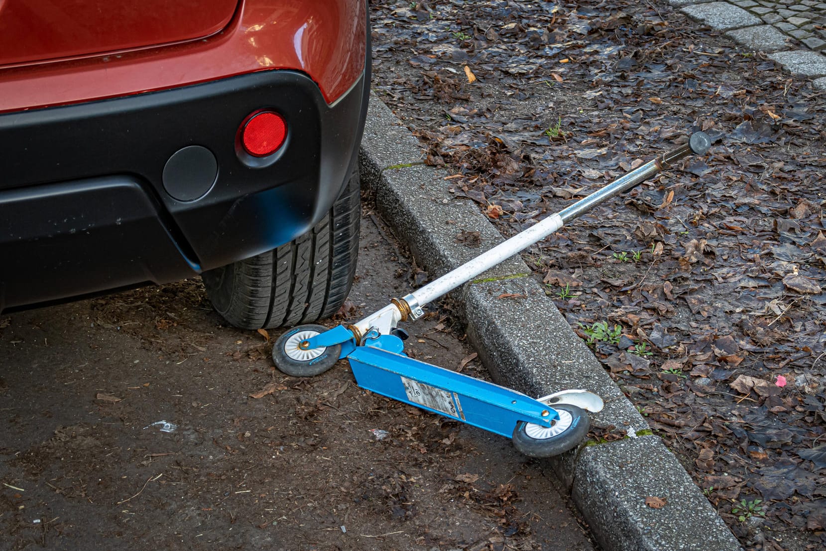 Ein Tretroller liegt nahe eines Autos (Symbolbild): In Wuppertal ist es zu einem Unfall mit einem jungen Rollerfahrer und einem Auto gekommen.