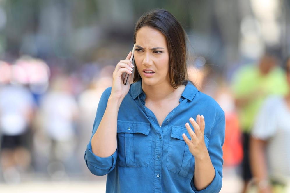 Eine genervte Frau am Handy: Vorsicht vor Spam-Anrufen.