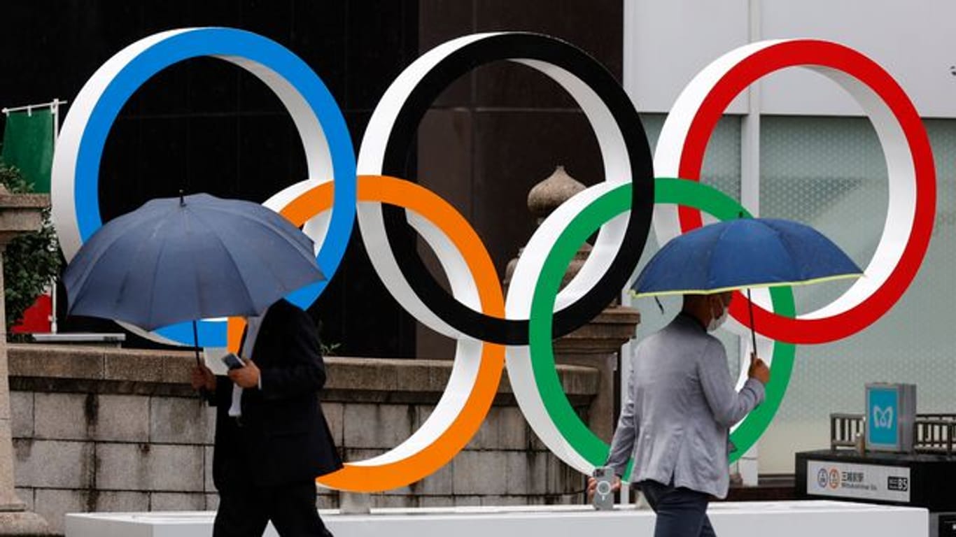 Passanten gehen an Olympischen Ringen in Tokio vorbei.
