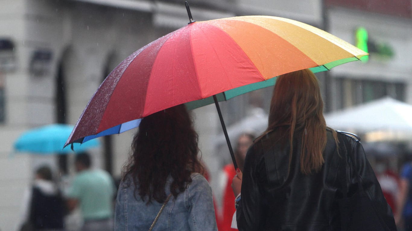 Personen gehen mit Regenschirm während eines Regenschauers in der Innenstadt (Symbolbild): In Bayern werden heftige Unwetter erwartet.