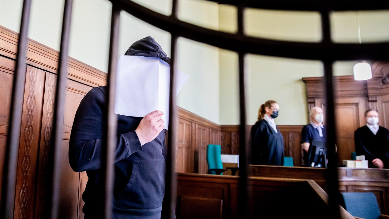 Der Angeklagte hält sich bei Prozessbeginn ein Blatt Papier vor das Gesicht: Der Mann ist wegen Mordes verurteilt worden.