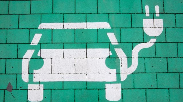 Auto-Symbol auf einem Parkplatz mit einer Ladesäule für E-Autos