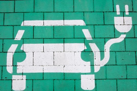 Auto-Symbol auf einem Parkplatz mit einer Ladesäule für E-Autos