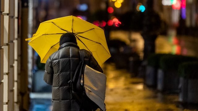 Ein Passant geht bei Regen durch die Stadt