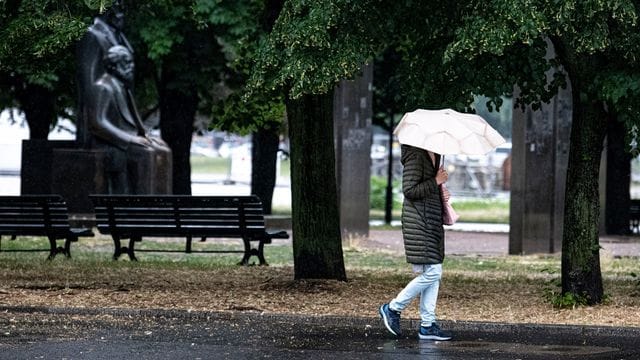 Eine Passantin geht bei Regen durch Berlin-Mitte