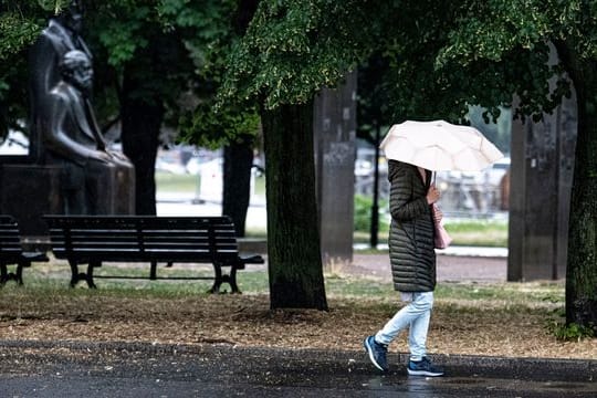 Eine Passantin geht bei Regen durch Berlin-Mitte