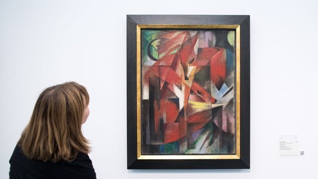 Eine Frau steht vor dem Gemälde "Füchse" von Franz Marc