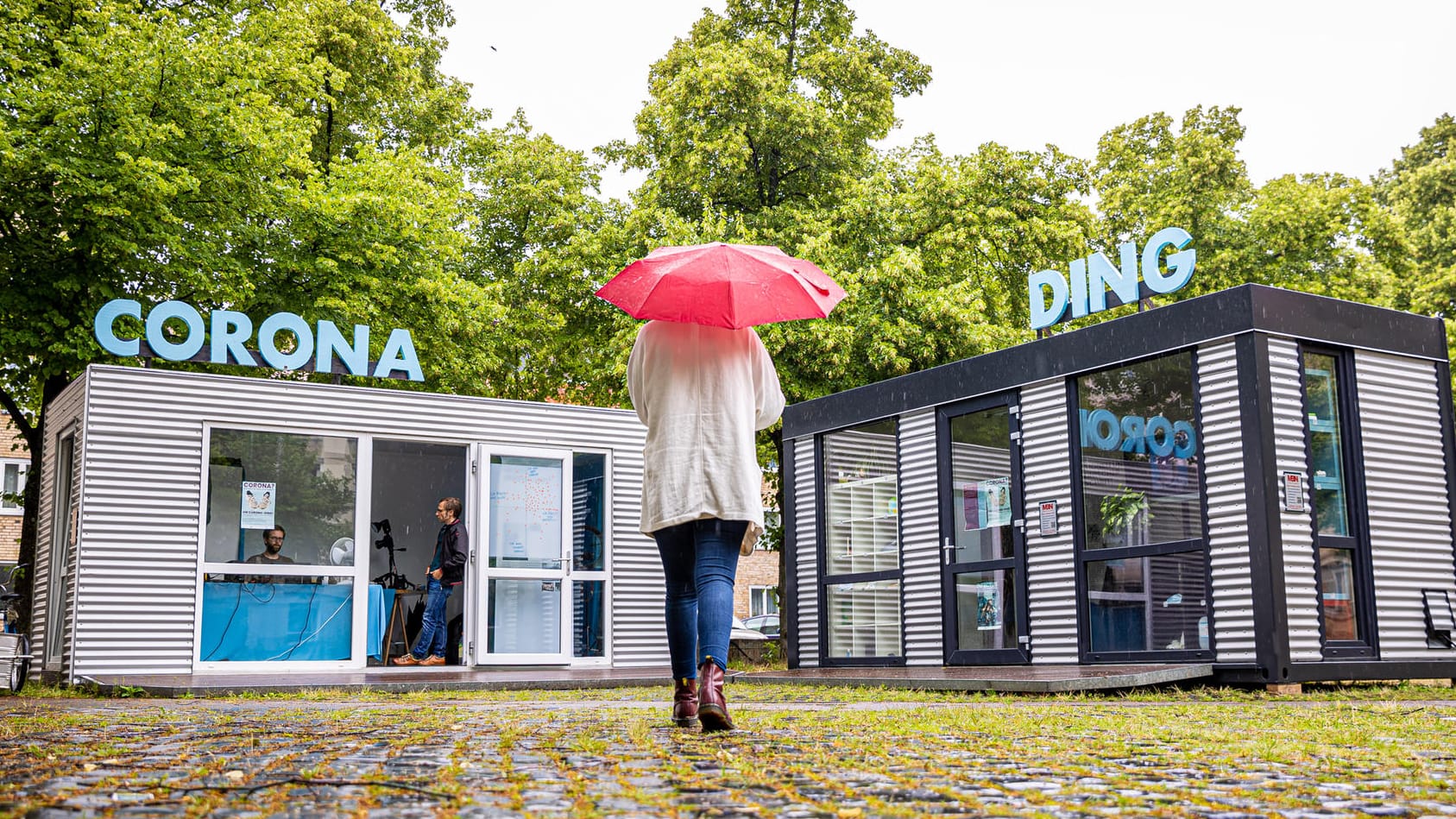 Eine Frau geht auf die Container der Ausstellung "Das Corona-Ding" zu: Das Projekt soll die aktuelle Pandemie für die Nachwelt dokumentieren. Eine Frau geht auf die Container der Ausstellung "Das Corona-Ding" zu: Das Projekt soll die aktuelle Pandemie für die Nachwelt dokumentieren.