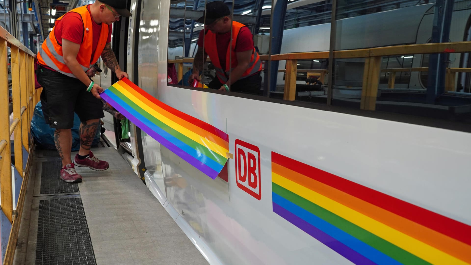 Ein Bahn-Mitarbeiter beklebt den Zug im ICE-Werk Berlin-Rummelsburg: Die Deutsche Bahn will mit dem bunten Zug das Engagement von Mitarbeitenden anlässlich des zehnten Jubiläums des LGBTIQI*-Netzwerks würdigen.